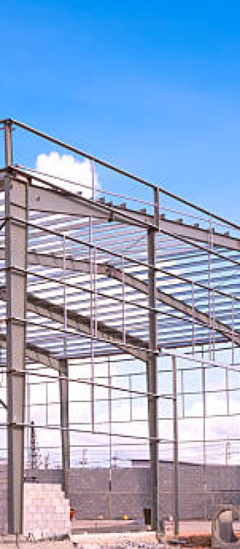 Metal column and roof beam structure of industry warehouse factory building with material in construction site against blue sky background, side view with copy space